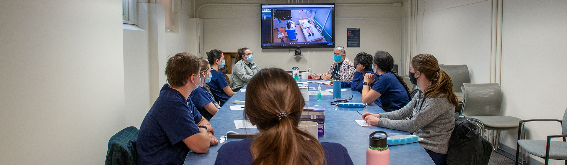 Students in class looking at screen and wearing masks
